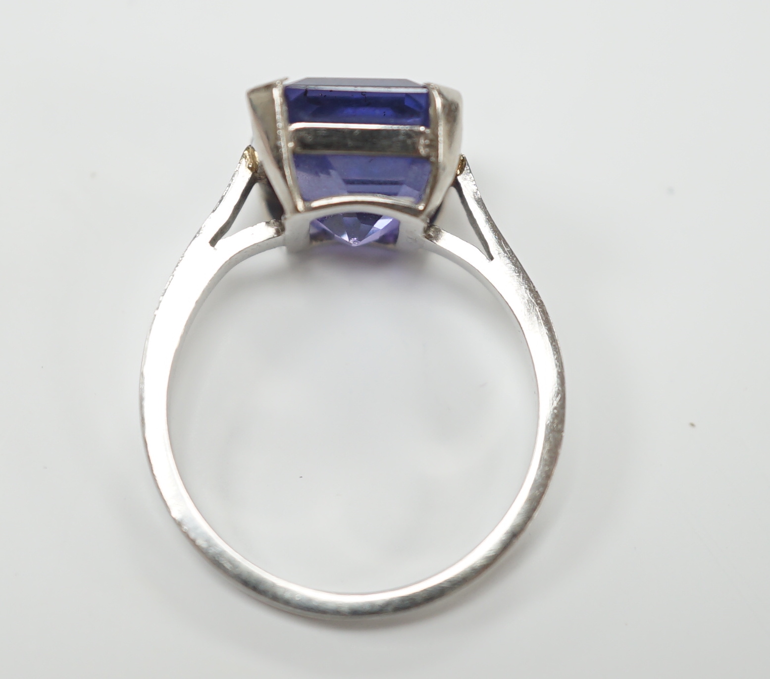 A white metal and single stone and square cut blueish purple sapphire set dress ring, size M, gross weight 5.6 grams, the stone measuring 10mm by 9,8mm, with a depth of 7.4mm.